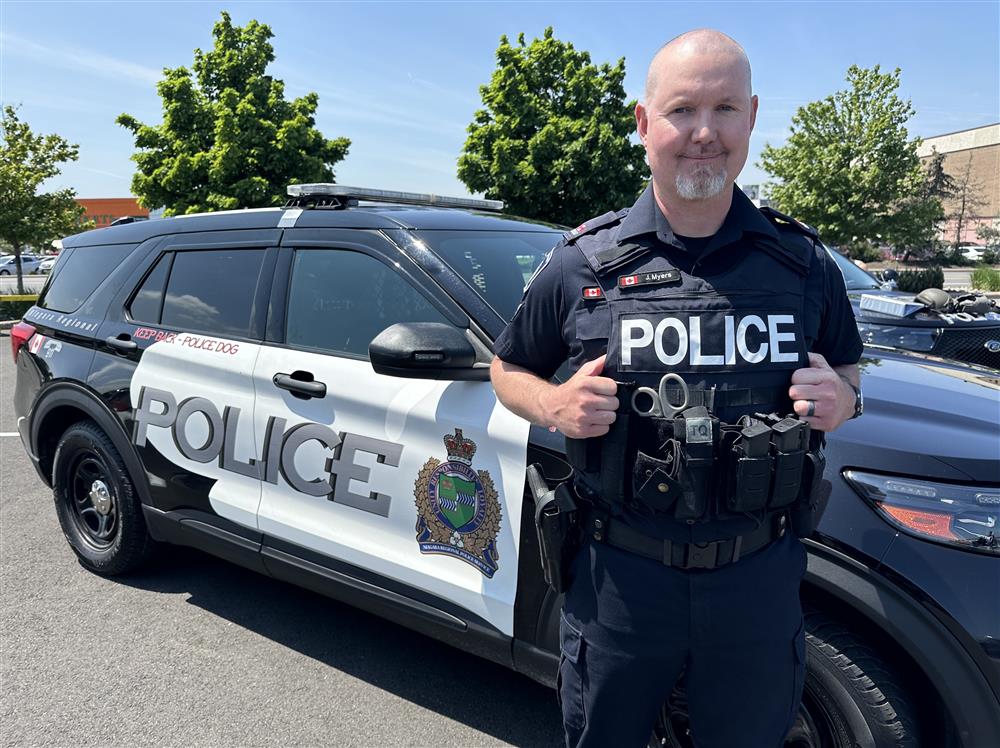 A police officer standing in front of a cruiser